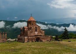 Photo by Ani Adigyozalyan brown concrete church on green grass field under white clouds during daytime