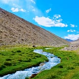 river in between brown mountains under blue sky during daytime