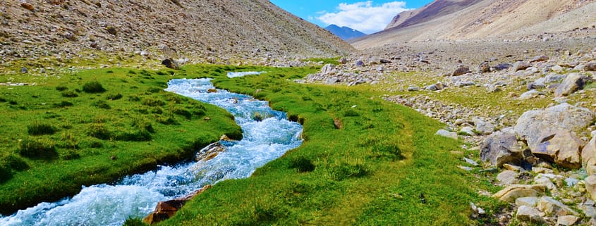 river in between brown mountains under blue sky during daytime
